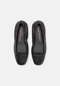 Zwarte leren platte schoenen met een ronde neus, voorzien van een klein strikaccent en een gladde textuur, met een minimaal ontwerp.