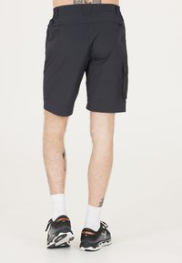 Sorte cargo shorts med en glat tekstur, der har en sidelomme og en tætsiddende design, parret med sorte træningssko og hvide sokker.