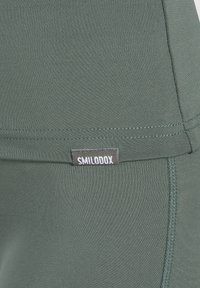 Zielone legginsy sportowe wykonane z gładkiego materiału. Posiadają metkę z logo "SMILODOX" oraz płaskie szwy dla uzyskania opływowego kroju.