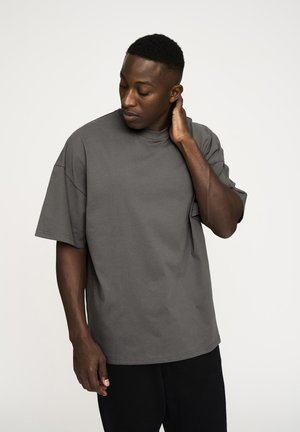 Grå oversized t-shirt med korte ærmer og rund hals, lavet af blødt bomuld. Viser en glat tekstur og afslappet pasform.