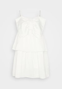 Robe blanche avec un grand nœud à l'avant, design à volants, bretelles réglables et tissu lisse et léger.