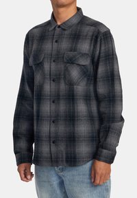 Schwarz-weißer kariert Flanellhemd mit langen Ärmeln, Knopfleiste, zwei Brusttaschen und geradem Saum. Textilstruktur mit subtilen Mustern.