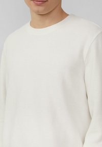 Weißes Langarmshirt aus strukturiertem Rippstoff, mit Rundhalsausschnitt und leicht lässiger Passform.