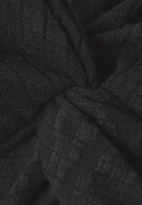 Schwarzer gestrickter Stoff mit einem strukturierten Muster, der einen weichen, gemütlichen Eindruck vermittelt. Das Material ist dicht und dennoch flexibel und zeigt filigrane Details.