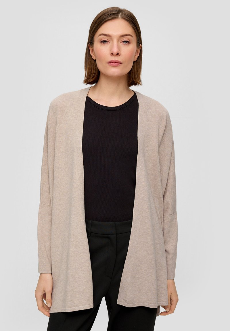 Beige open-front cardigan met lange mouwen. Zacht, lichtgewicht materiaal, rechte snit en verlaagde schouders. Gelaagd over een zwarte ribbed top.