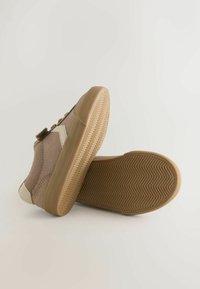 Brune ruskinds sneakers med gummisål. Designet har hvide accentpatches og et struktureret fiskebensmønster på bunden.