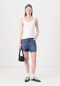 Bílý bezrukávový top, modré džínové šortky, černá kabelka, bílé ponožky, černé špičaté baleríny. Jednoduchý design, ležérní střih, hladká textura.