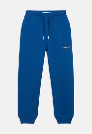 Blue Calvin Klein sweatpants with elastic waistband, drawstring, cuffed ankles, and logo on upper thigh.