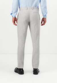 Ανοιχτό γκρι παντελόνι με υφή, ίσια γραμμή, θηλύκια ζώνης και μία πίσω τσέπη, συνδυασμένο με μαύρα παπούτσια.