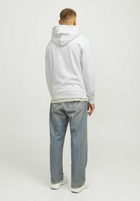 Grijs hooded sweatshirt met een relaxed fit, gecombineerd met lichtblauwe denim jeans. Het sweatshirt heeft een kenguruzak en geribbelde manchetten.