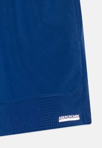 Navy blue shorts in a lightweight fabric with a grid texture at the hem. Features an embroidered label on the lower left side.