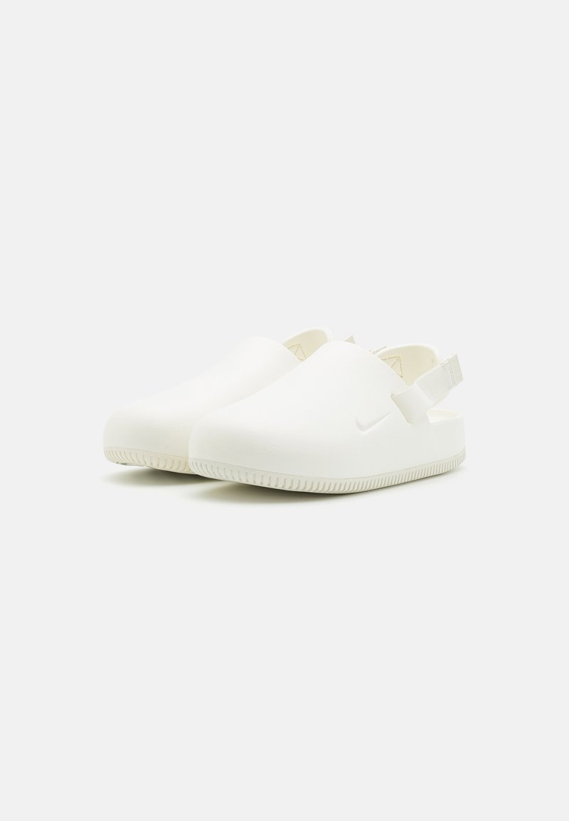 Zuecos blancos de tipo slip-on con un acabado de goma lisa, que cuentan con una correa trasera y una suela texturizada para mayor agarre. Incluyen un pequeño logotipo como acento.