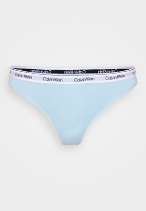 Lichtblauwe stringonderbroek met een zwarte elastische tailleband waarop witte "Calvin Klein" branding staat. Gladde stof met minimale stikseldetails.