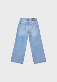 Jeans in denim azzurro chiaro a gamba larga distesi, visti da dietro con due tasche e un'etichetta nera del marchio sulla vita.