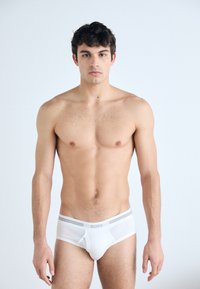 Weiße Baumwollslips mit grauem Bund, im klassischen Schnitt. Glatte Textur, minimalistisches Design und keine sichtbaren Muster oder Verzierungen.