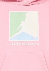 Ροζ φούτερ με κουκούλα που διαθέτει εμπρόσθιο γραφικό με λευκή σιλουέτα και πολυχρωμο φόντο σε πράσινο και μπλε, με τη λέξη «JORDAN» από κάτω σε λευκό κείμενο.