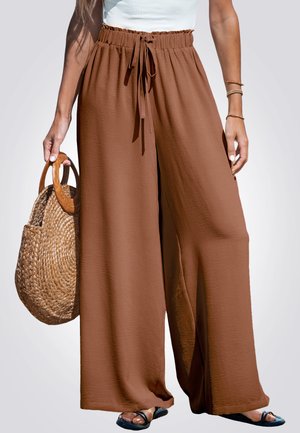 Brown wide-leg pants with a drawstring waist, made of a textured material. Paired with a woven straw bag and black sandals.