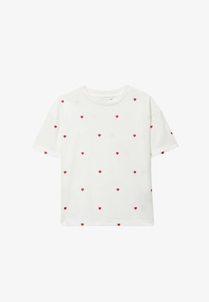 Chemise blanche à manches courtes avec de petits motifs rouges en forme de cœur éparpillés, dotée d'un col rond et d'une coupe décontractée.