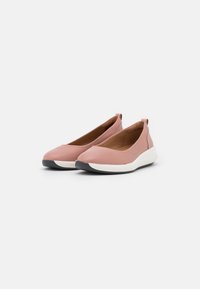 Scarpe slip-on rosa realizzate in materiale morbido con punta arrotondata, suola intermedia bianca e suola esterna nera in gomma. Accentuate da dettagli di cucitura minimi.