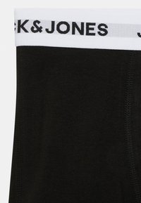Caleçons boxers en coton noir avec une ceinture élastique blanche portant la mention "JACK & JONES" imprimée en noir, texture lisse et sans motifs visibles.