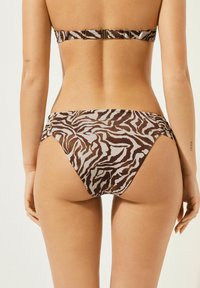 Brun och beige bikiniunderdel med ett zebra-randigt mönster, med en låg midja och veckad detaljer vid sidorna. Mjuk, slät tyg.