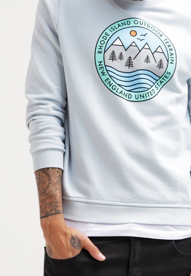 Sweat-shirt bleu clair avec un logo circulaire montagne, arbres, rivière et soleil intitulé Rhode Island Outdoor Terrain New England United States.