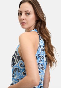 Mouwloze jurk in blauwe tinten met een bloemenpatroon en een open rug. Gemaakt van lichte stof met een gladde textuur.