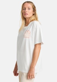 Weißes Baumwoll-T-Shirt mit lockerer Passform, Rundhalsausschnitt und kurzen Ärmeln. Die Vorderseite zeigt ein dezentes orangefarbenes Grafikdesign mit Palmen und Sonne.