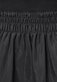 Svart kjol med ribbhetspassform och draperad tygstruktur, tillverkad av lätt material med en mjuk yta.