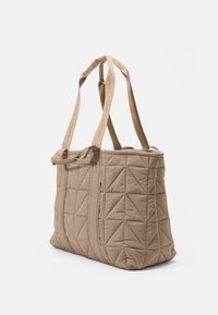 Bolsa tote acolchada beis con patrones triangulares prominentes, dos largas asas de tela y un cierre superior con cremallera para un acceso seguro.