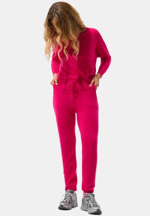 Set di abbigliamento loungewear fucsia composto da una maglietta a maniche lunghe e pantaloni con coulisse. Texture morbida, vestibilità rilassata, con tasche laterali e cuciture minime.