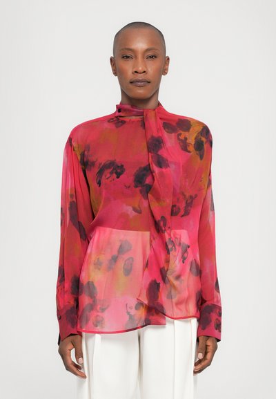 Bluză transparentă de culoare roz, cu modele florale abstracte în roșu și negru, cu guler înalt și mâneci lungi. Textură netedă, design drapat.