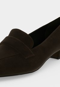 Mocassin en cuir marron foncé à petit talon avec un bout pointu et une large bride sur le dessus avant.