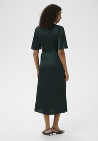 Rochie midi din satin verde, cu mâneci scurte și o curea la talie. Textură netedă, cu o siluetă fluidă și o margine până la genunchi.