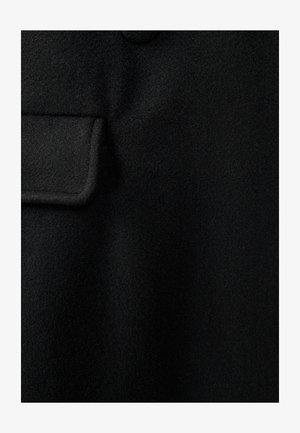 Melna vilnas žakete ar nedaudz teksturētu virsmu, ar kabatu un apaļas pogas detalizāciju uz apkakles.