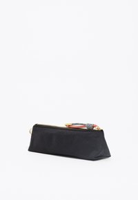 Estuche negro hecho de tela suave, con una cremallera dorada, un tirador de cremallera texturizado en gris y rojo, y con forma triangular.