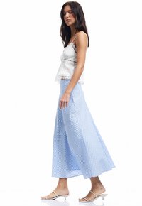 Top de camisón de encaje blanco combinado con una falda larga y fluida a cuadros azul y blanco. Sandalias planas simples completan el conjunto.