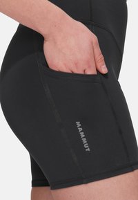 Pantaloni sportivi neri realizzati in tessuto elasticizzato, dotati di tasca laterale e cuciture a contrasto, con il logo "MAMMUT" stampato sulla gamba.