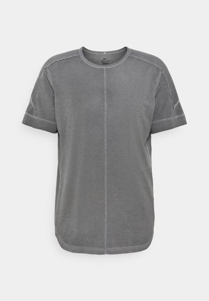 T-shirt de sport gris à manches courtes avec col rond et détails de coutures visibles sur le devant et les manches.