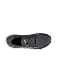 Baskets de sport gris foncé avec un dessus en mesh texturé, des accents rayés verts et une semelle en caoutchouc blanc. Présente un laçage traditionnel et une languette rembourrée.