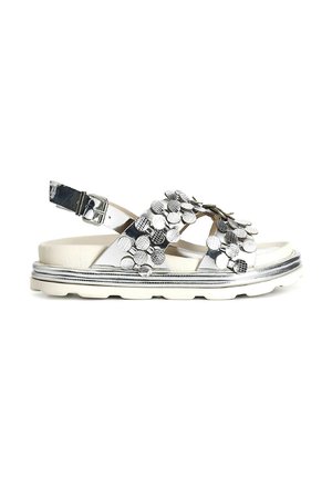 Sandal con sole piatto in bianco e argento, caratterizzato da un design con punta aperta e decorazioni a disco metallico sulle cinghie. Con fibbia regolabile alla caviglia.