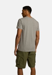 Szara koszulka z krótkim rękawem wykonana z bawełny, połączona z oliwkowymi szortami cargo z bocznymi kieszeniami i luźnym krojem.