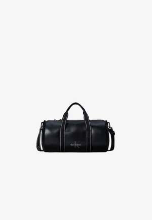 Μαύρη κυλινδρική τσάντα τύπου duffel Calvin Klein με διπλές χειρολαβές στην κορυφή και αποσπώμενο ιμάντα ώμου σε λευκό φόντο.