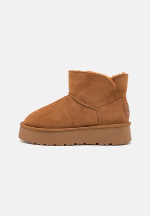 Bottine en daim brun avec doublure en peluche, semelle épaisse et détail de couture latérale, conçue pour un usage décontracté.