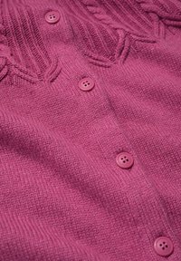 Cárdigan de punto rosa con un patrón texturizado en la parte superior, que cuenta con botones redondos rosas en la parte frontal.