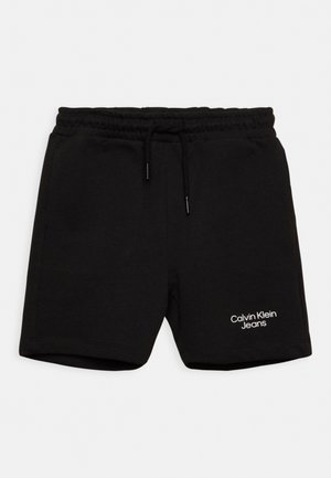 Pantaloni corti neri in cotone con vita elasticizzata e cordoncino, caratterizzati da un logo bianco "Calvin Klein Jeans" sulla gamba sinistra.