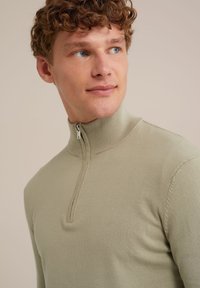 Šviesiai žalias užtrauktukas megztinis, pagamintas iš minkštos mezginio medžiagos. Akcentuojamas išklotas apykaklė ir lygus audinys, sukurtas prigludusiai silueto formai.