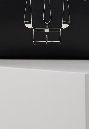 Zwart bord met witte contour van een persoon die een pak en stropdas draagt boven een wit rechthoekig oppervlak of plank.