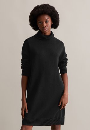 Schwarzes Rollkragenkleid aus einem weichen Stoff. Mit gerippten Bündchen und Saum, im lässigen Schnitt, das gerade oberhalb des Knies endet.