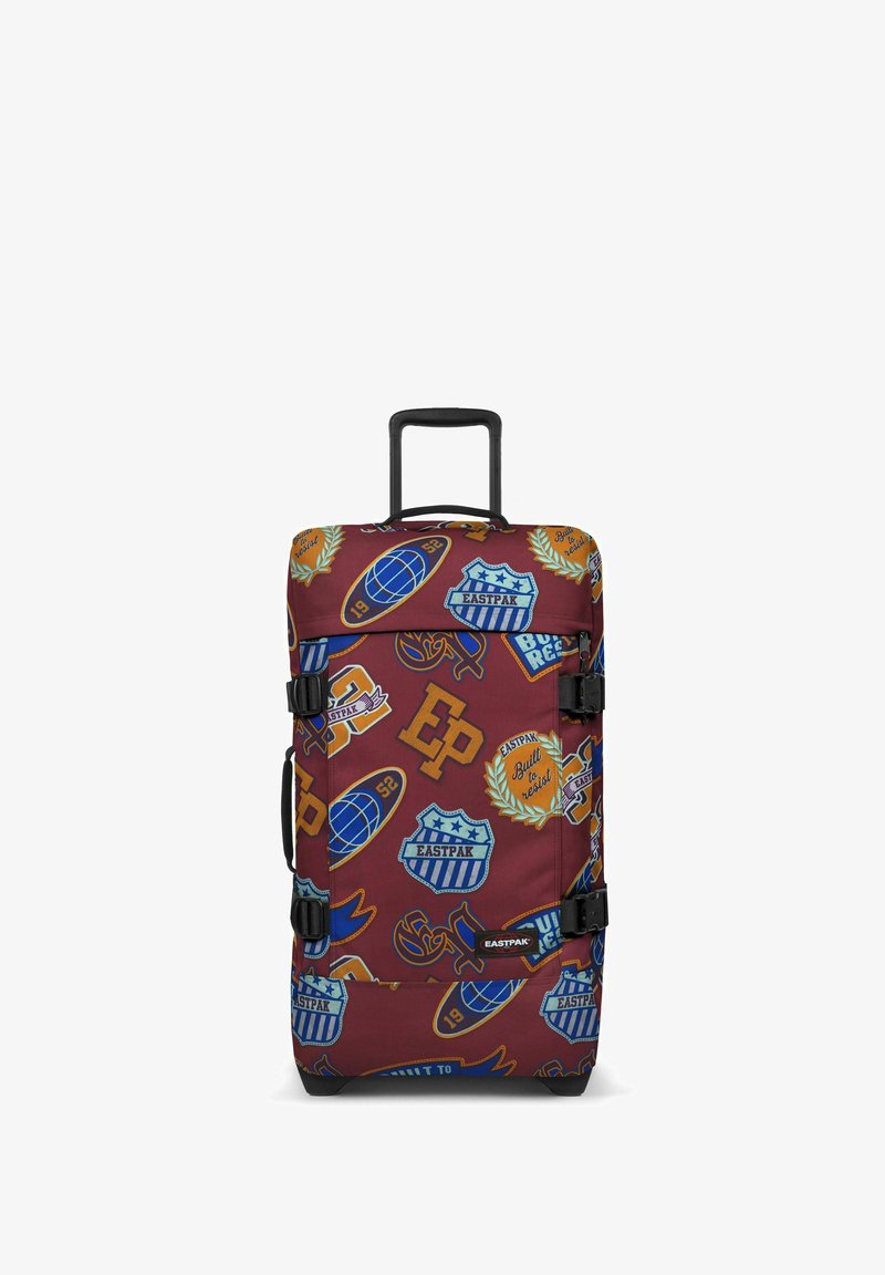 Borsa da viaggio in tessuto rosso con diversi toppe a tema sportivo di vari colori, dotata di manici e fibbie nere, manico estensibile e base rinforzata.